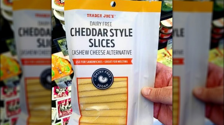 Hand holds a package of Trader Joe's Dairy Free Cheddar Style Slices