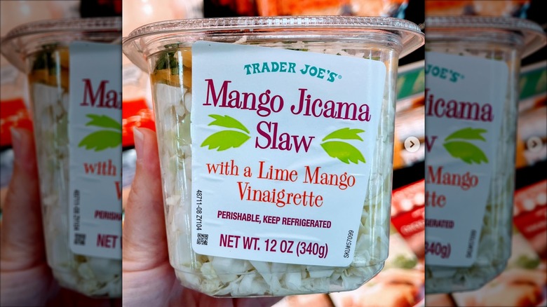 Hand holding a container of Trader Joe's Mango Jicama Slaw