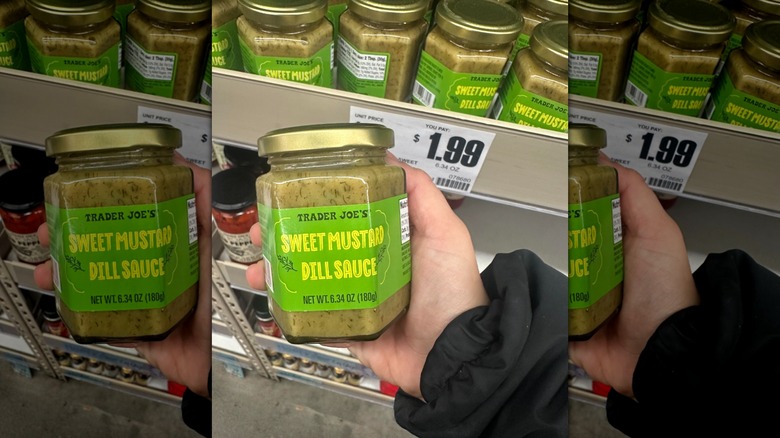 Hand holds a jar of the Trader Joe's Sweet Mustard Dill Sauce