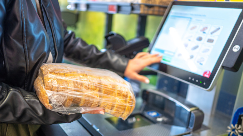 A shopper scanning bread at self-checkout