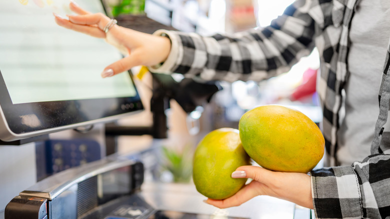 A woman buying mangoes at self-checkout