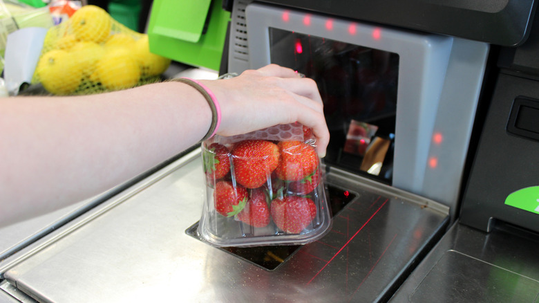 A person scanning a container of strawberries at self-checkout