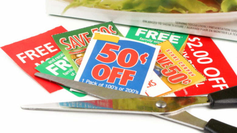Scissors on a white surface with grocery coupons