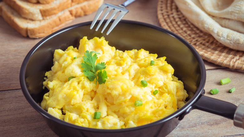 Scrambled egg in pan with fork and toast