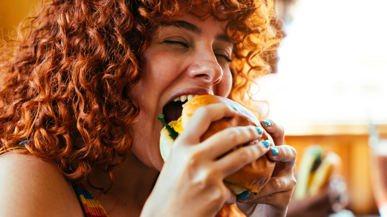 woman eating fast food hamburger