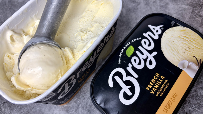 A carton of Breyers French Vanilla ice cream open with ice cream scoop inside the carton