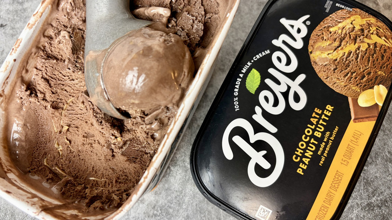 A carton of Breyers Chocolate Peanut Butter ice cream opened with ice cream scoop dipping into the ice cream