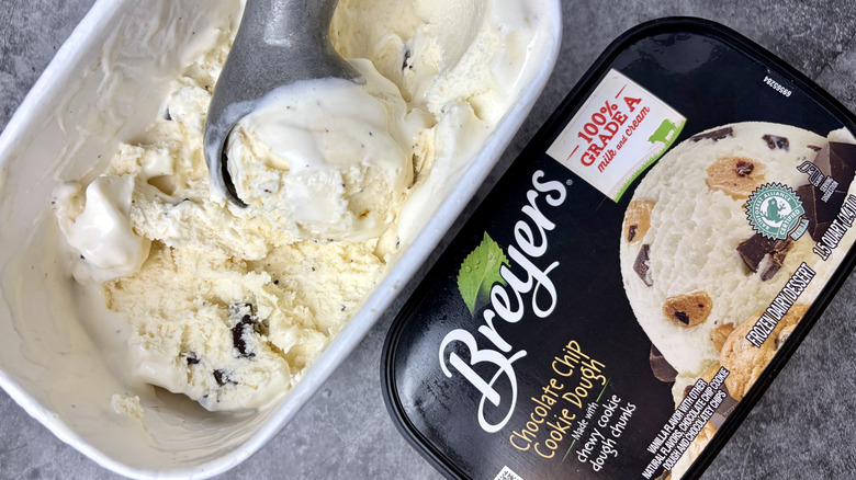 A carton of Breyers Chocolate Chip Cookie Dough ice cream opened with ice cream scoop inside the ice cream