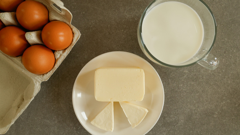 An overhead shot of eggs, milk, and butter on a counter