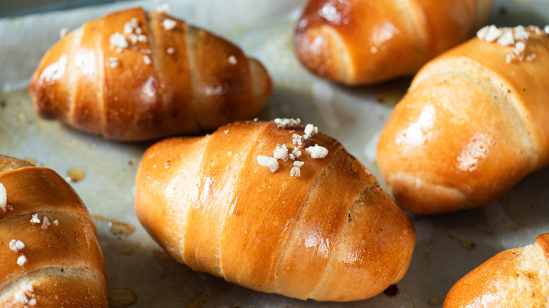 Freshly baked dinner rolls in a crescent shape on a baking sheet