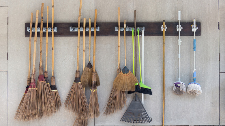 Brooms, mops, and rakes hanging from a wall-mounted organizer