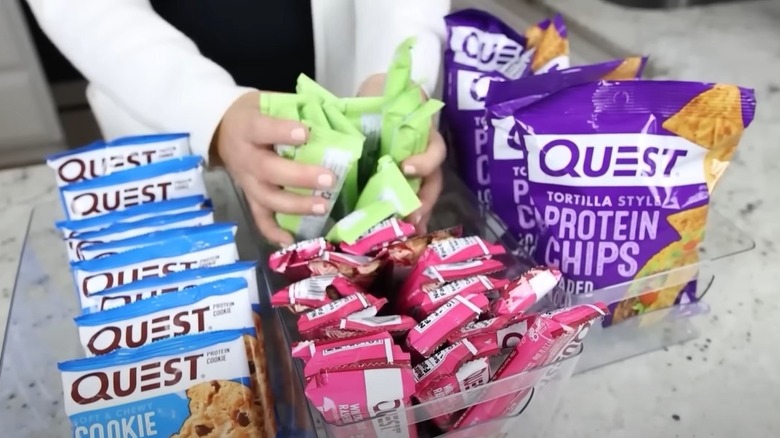 A woman organizes snacks into three clear, acrylic organizers