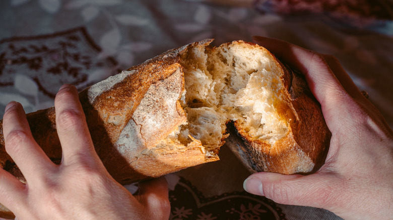Hands breaking French bread