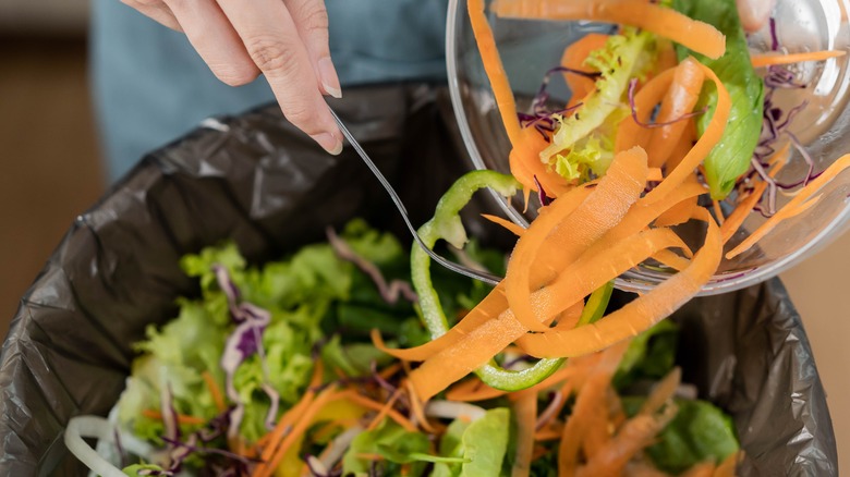 Woman tossing kitchen waste in the bin