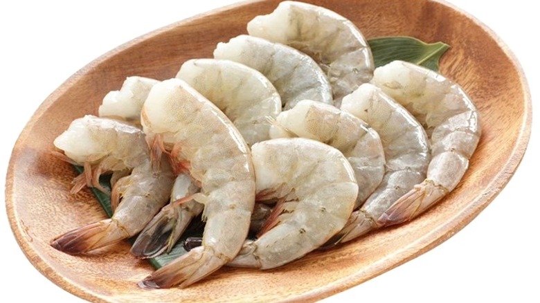 Wooden bowl with several raw jumbo shrimp.
