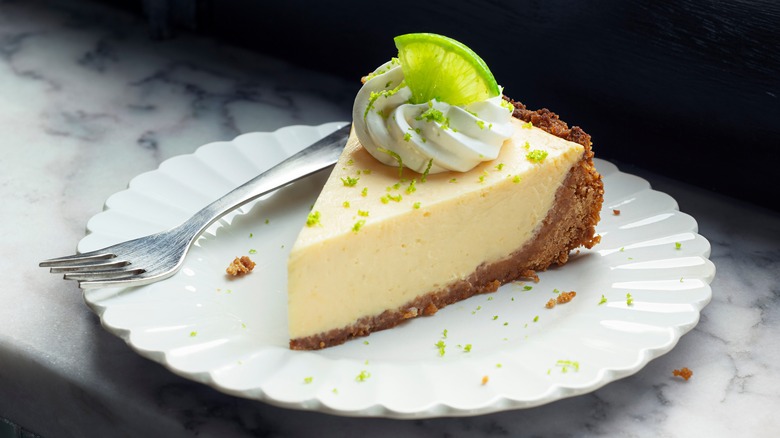 Slice of key lime pie on fluted white plate