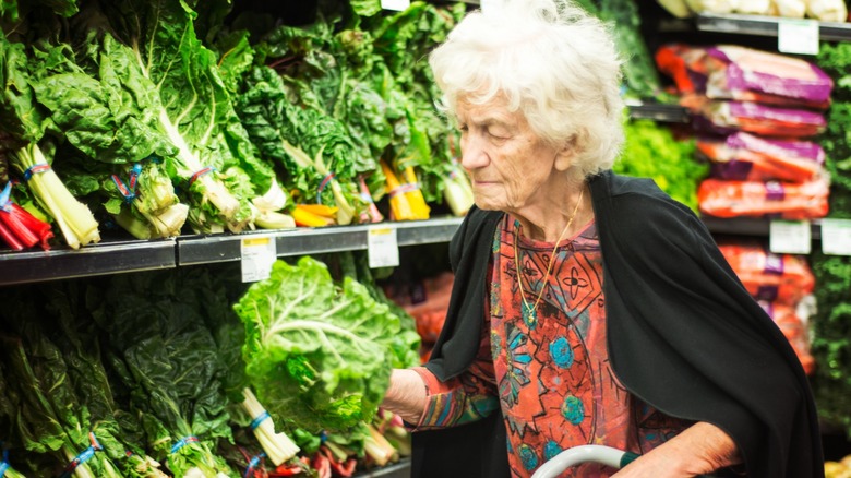 older woman examining lettuce