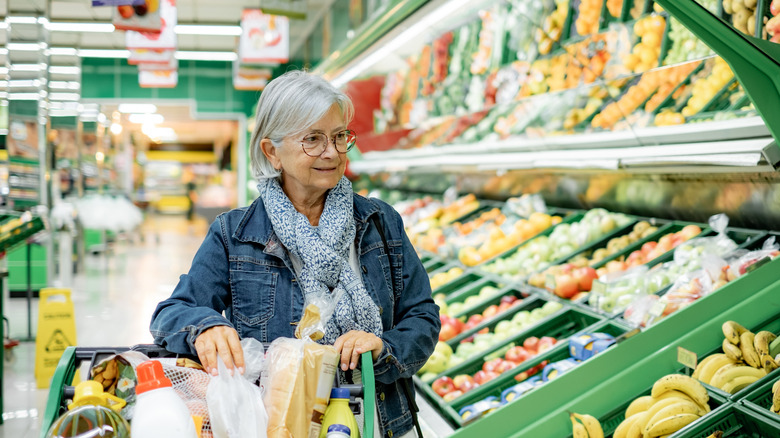 an older woman with gray hair shopping for fruit