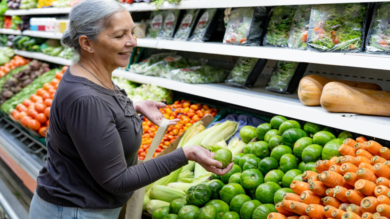 an older woman with gray hair shopping for produce