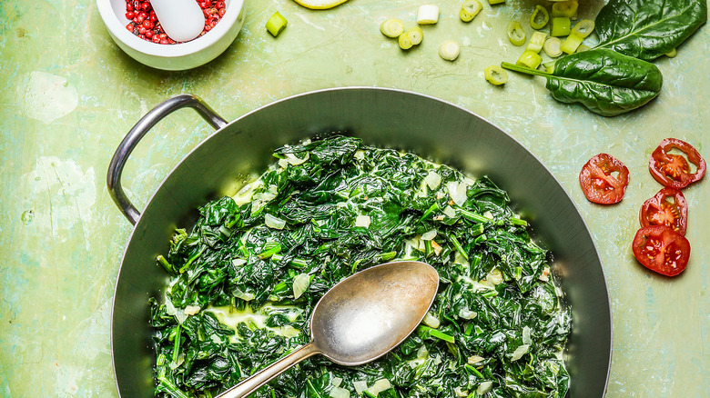 Creamed spinach in a pot with a spoon and chilis