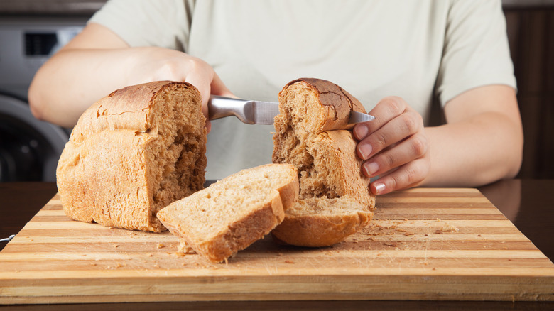 Person slicing loaf of bread