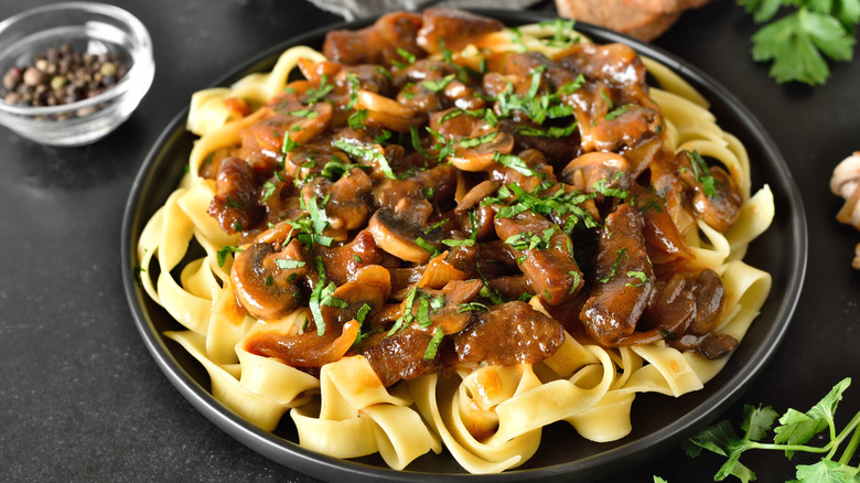Beef Stroganoff on a black plate garnished with chopped parsley
