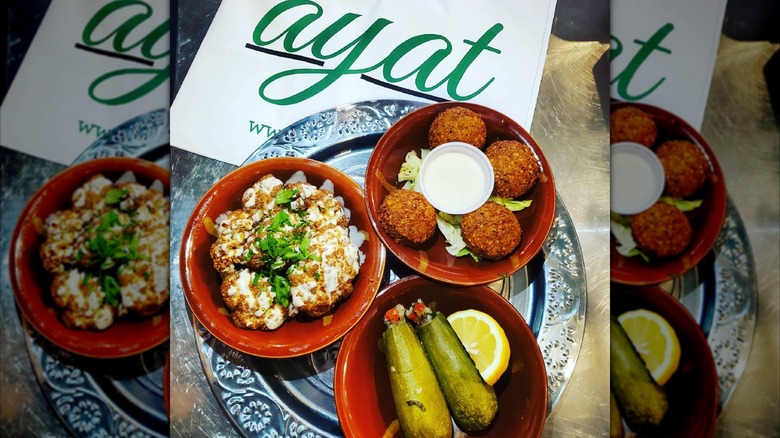 Plate with dishes of food and Ayat logo on card