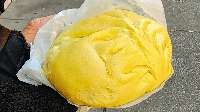 Hand holding steamed dumpling on city street