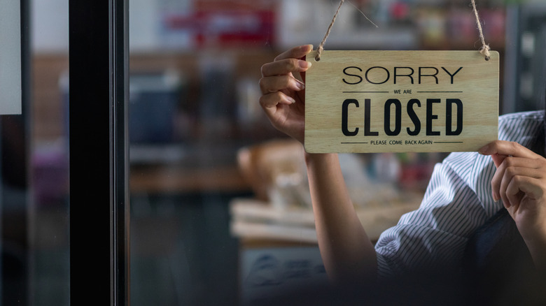 Unidentified person hanging a "Closed" sign on the door