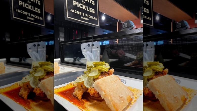 Dish of chicken, pickles, and biscuit in front of Jacob's Pickles sign