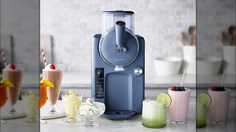 Frozen drink and ice cream maker on kitchen counter surrounded by desserts and beverages.