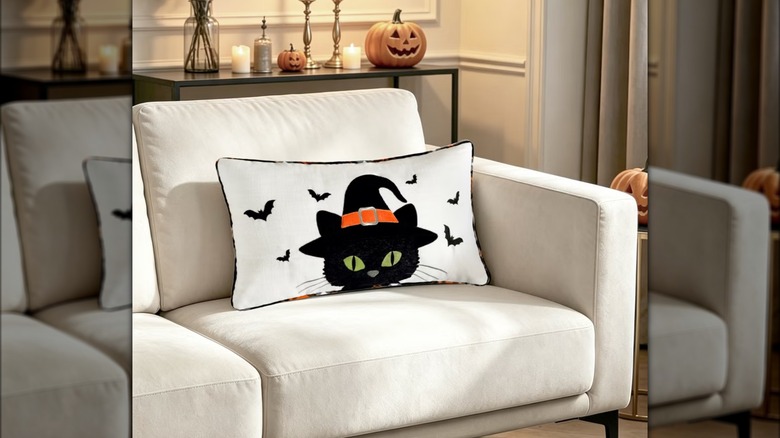 Halloween throw pillow with black cat on white couch.