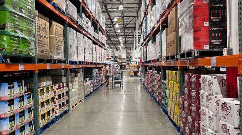 Shopper with cart in Costco aisle.