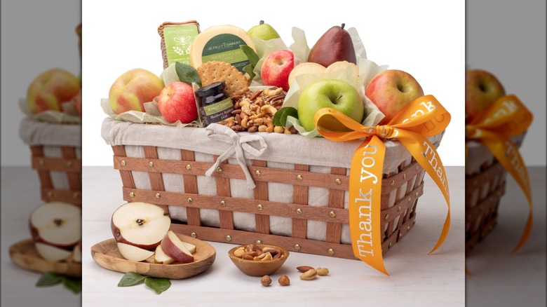 Gift basket with assorted fruit, cheese, nuts, and other foods.