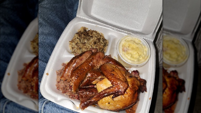 barbecue chicken, rice, and mac and cheese in a white styrofoam takeout container