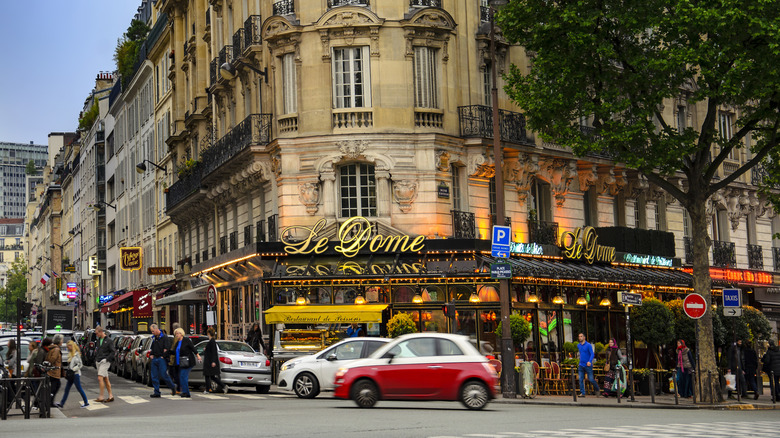 Le Dome Cafe on a Parsian street corner with traffic driving by