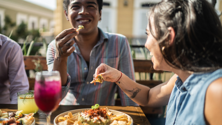 young adults laughing and eating appetizers at restaurant