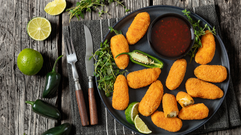 fried jalapeños with ingredients on side, fresh lime, and cup of dipping sauce