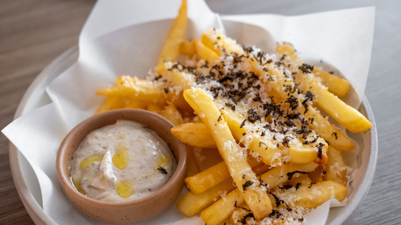 truffle fries in bowl topped with cheese and a side of dipping sauce
