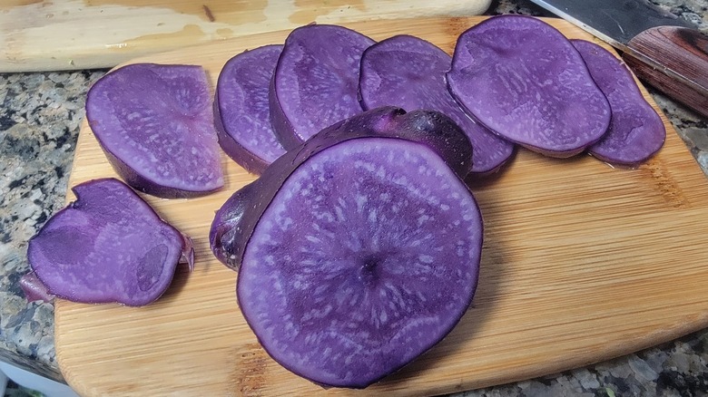 A sliced Adirondack Blue potato on a cutting board