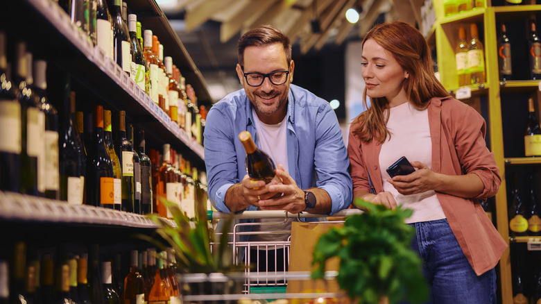A young man and woman browsing a selection of wine in the grocery store