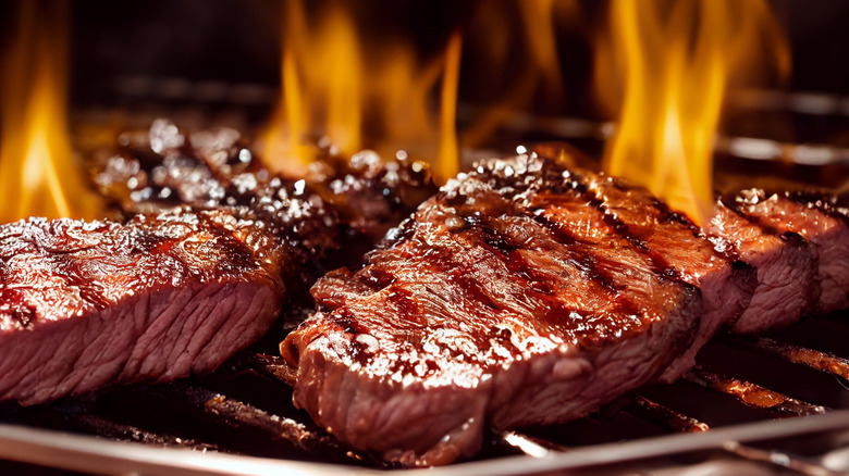 A bone-in steak with herbs on a smoky grill
