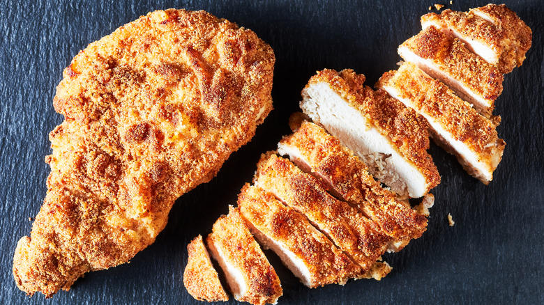 Two fried chicken cutlets, one is whole and the other is sliced