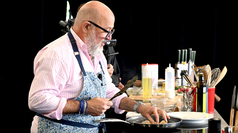 Andrew Zimmern placing meat in a pan