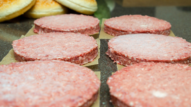 Frozen hamburger patties defrosting on a counter