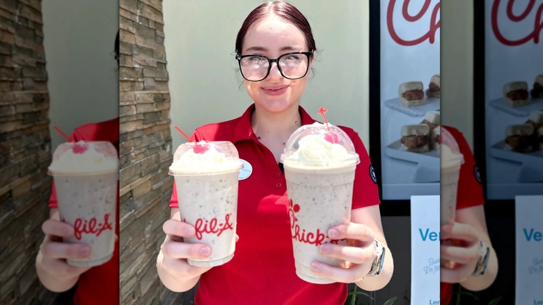 A Chick-fil-A employee holding two milkshakes