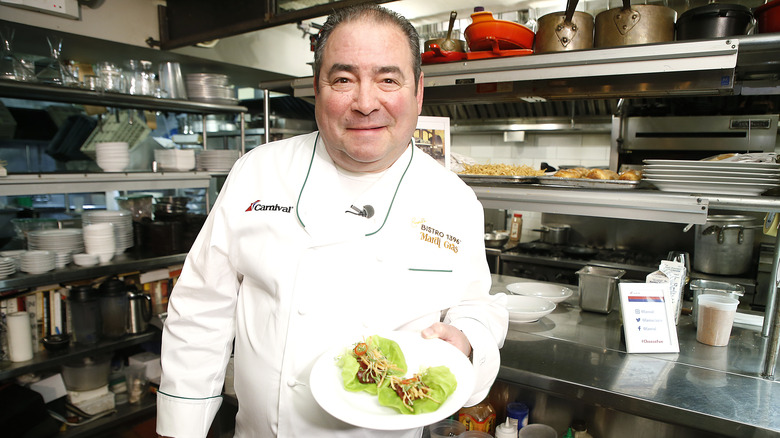 smiling Emeril holding a plate of food 