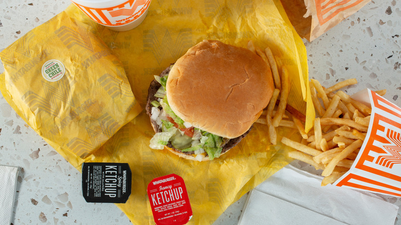 A Whataburger meal with a burger, fries, soda, and sauces