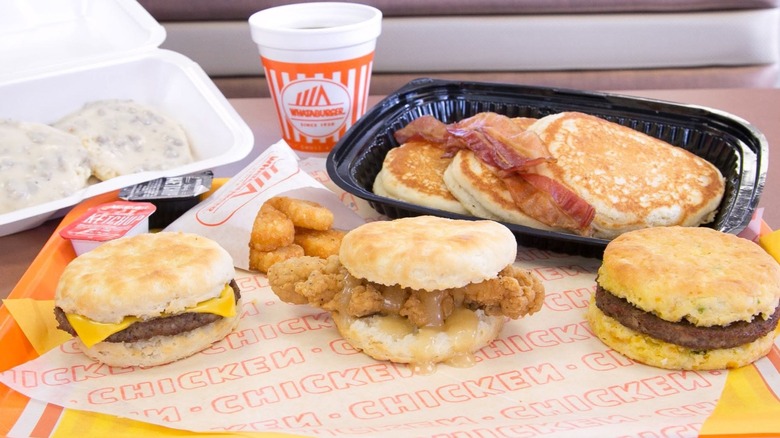 Whataburger breakfast spread with pancakes, bacon, hash browns, biscuits and gravy, breakfast sandwiches, and coffee on a tray