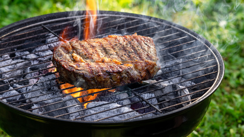 Steak cooking on charcoal grill